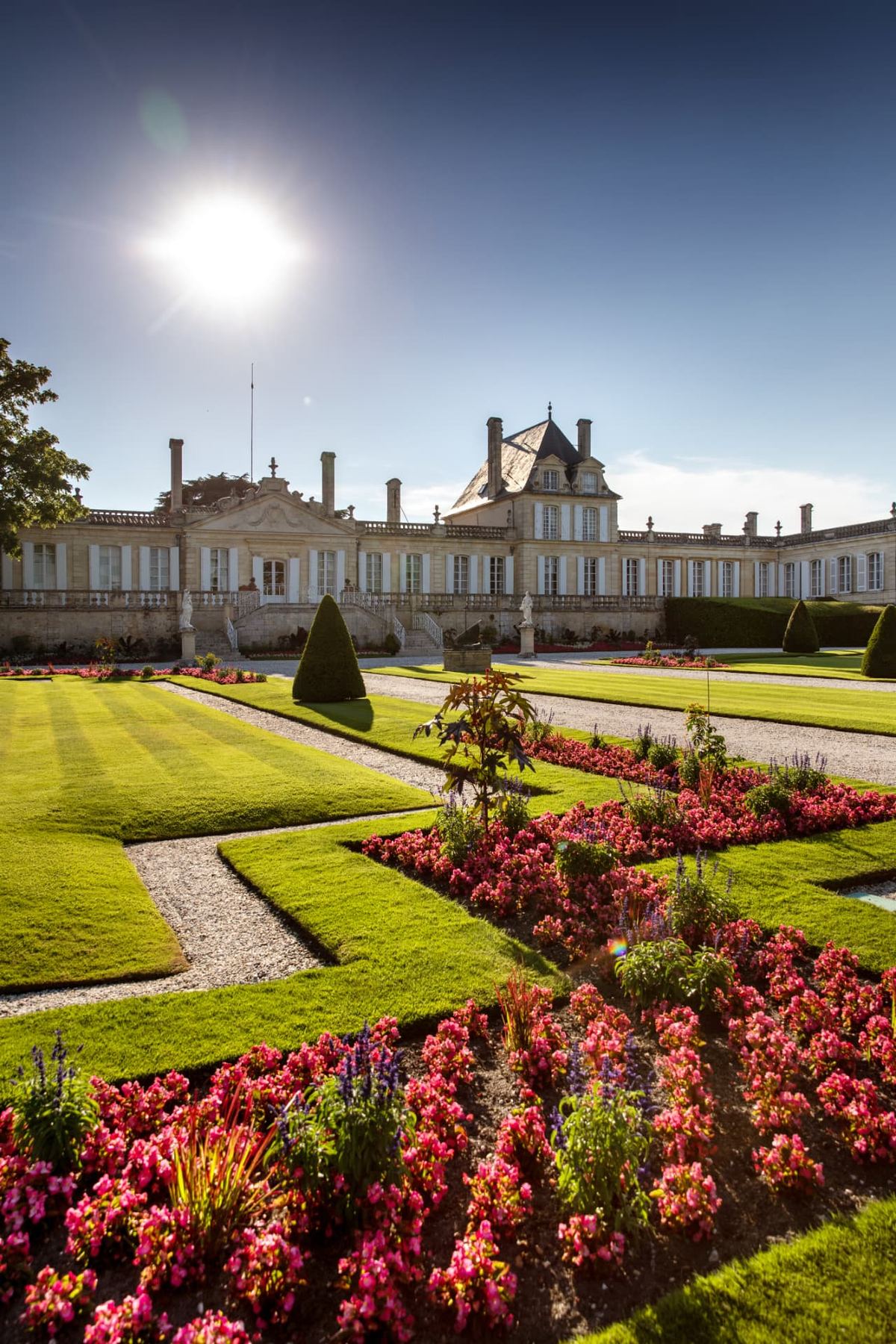 Château Beychevelle in Bordeaux, with formal gardens and flower beds in summer sunlight